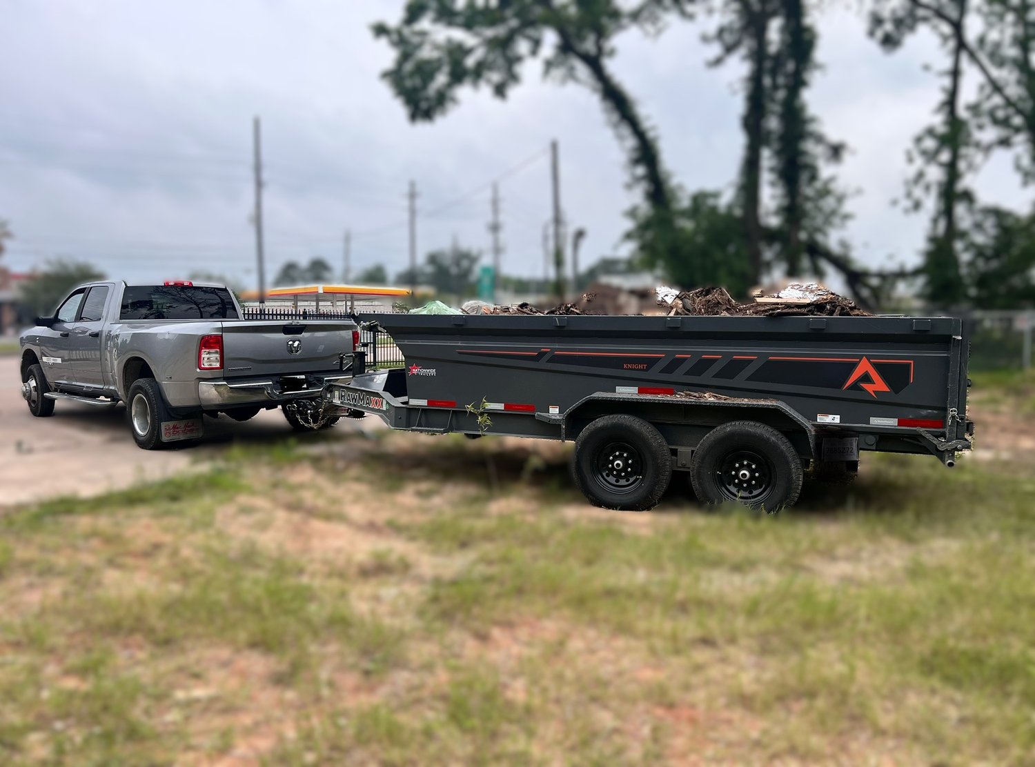 Knight dump trailer filled with debris being towed by a Ram truck.
